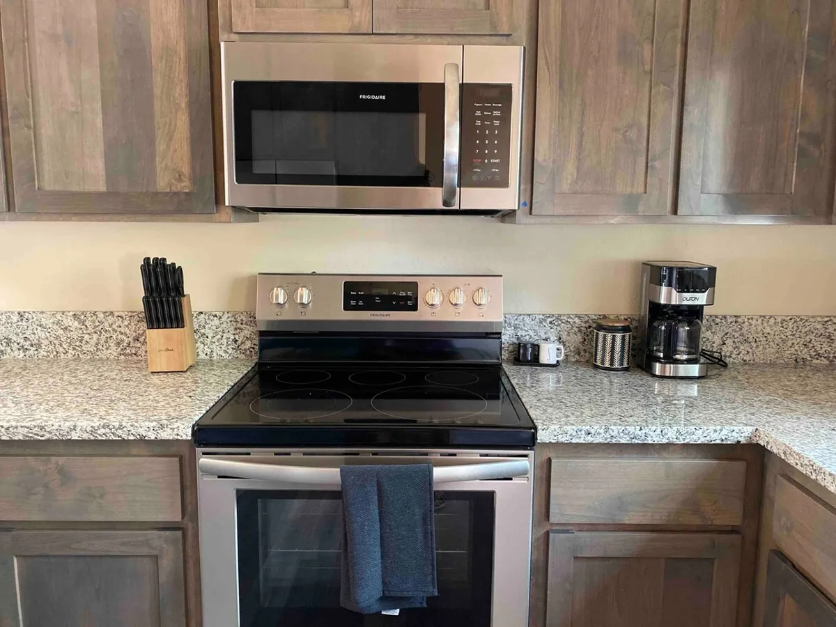 A close-up view of kitchen essentials, including stainless steel appliances, granite countertops, and utensils, showcasing both form and function. The setup is practical yet inviting, underscoring the kitchen's readiness for any culinary endeavor.